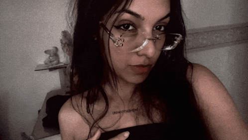 a woman wearing glasses has a tattoo on her shoulder that says fromotherhem