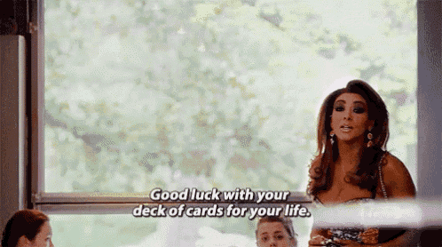 a woman is standing in front of a window and says `` good luck with your deck of cards for your life . ''