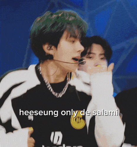 a man with green hair is wearing a black and white shirt with the word heeseung on it