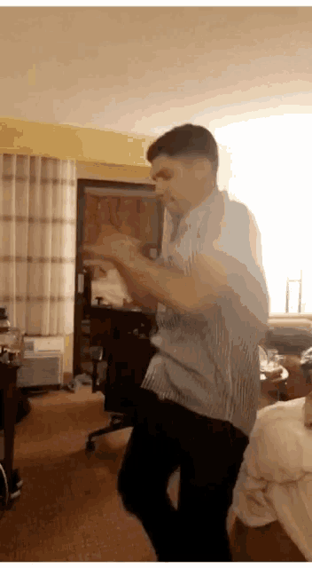 a man in a blue shirt is dancing in a living room