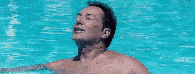 a man is swimming in a pool and his eyes are closed
