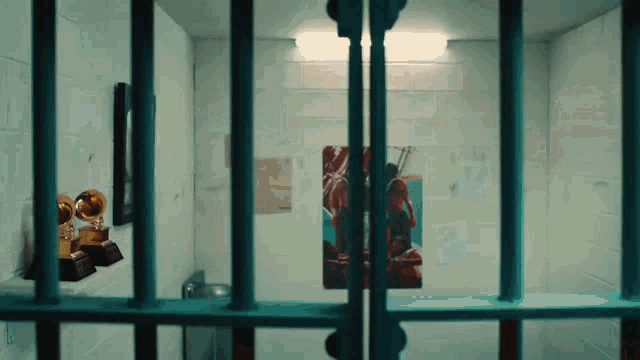 a prison cell with a painting on the wall and trophies on the shelf