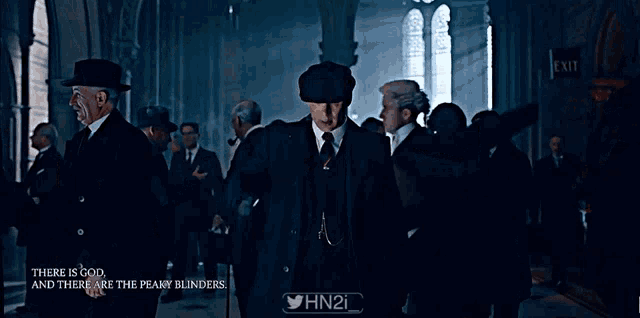 a man in a suit and hat says " we are much much closer at hand than god " in a dark room