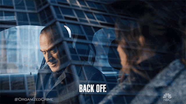 a man sitting in a car talking to a woman with the words back off below him