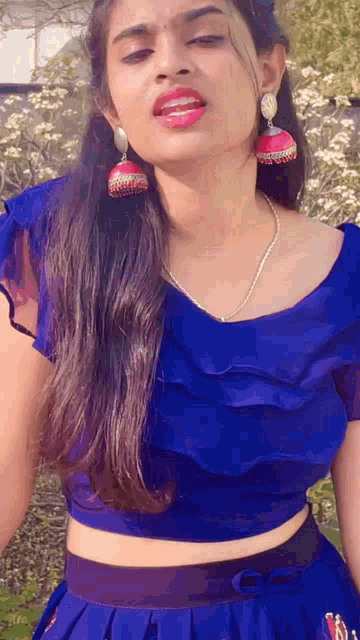 a woman wearing a blue crop top and a blue skirt