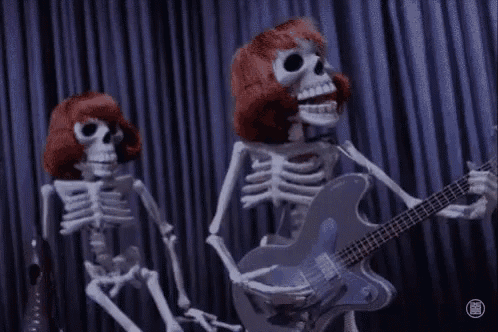 two skeletons are playing guitars in a dark room .