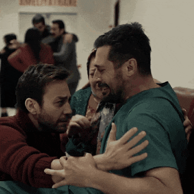 a man in a green scrub is being comforted by another man