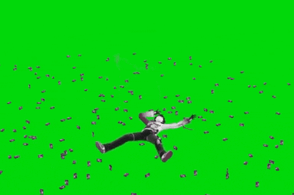 a man is laying on the ground with a green screen in the background surrounded by confetti .