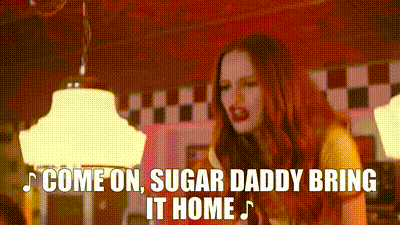 a woman with red hair is singing a song in a diner and the words `` come on , sugar daddy bring it home '' .