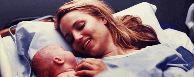 a woman in a hospital gown holds a newborn baby