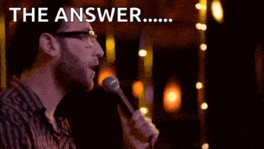 a man singing into a microphone with the words " the answer " behind him