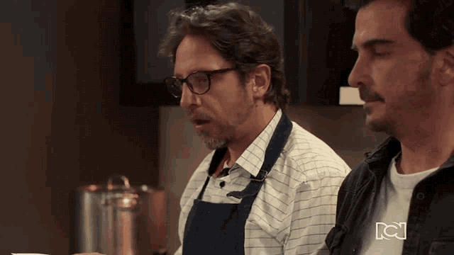 two men are standing in a kitchen with a rcj logo on the bottom right