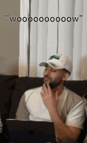 a man sitting on a couch with his hand on his chin and the words " wooooooow " written above him