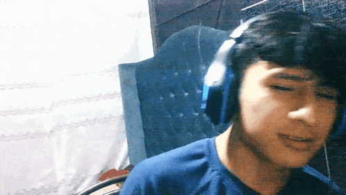 a young boy wearing headphones is looking at the camera .