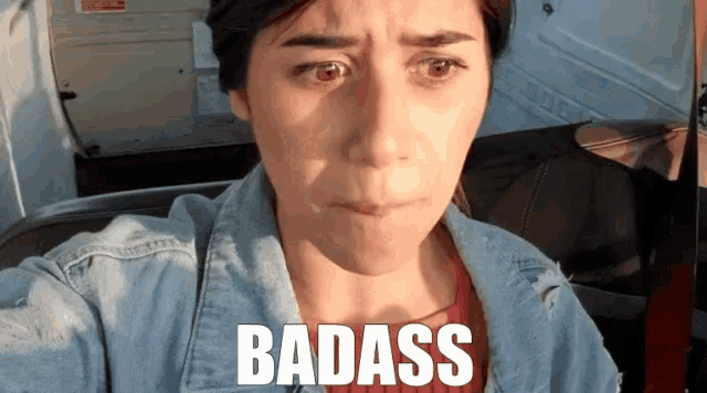 a woman wearing a denim jacket is making a face and the word badass is above her