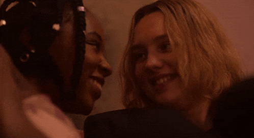 a close up of two women looking at each other and smiling .