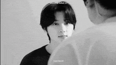 a black and white photo of a young man looking at another man .