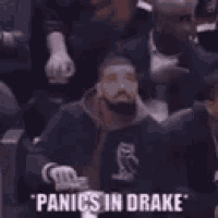 a man in a white tank top is standing next to a man in a black shirt and says `` panics in drake '' .