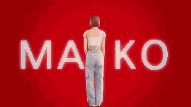 a woman stands in front of a red background that says " mako "