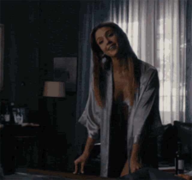 a woman in a robe is standing in a bedroom