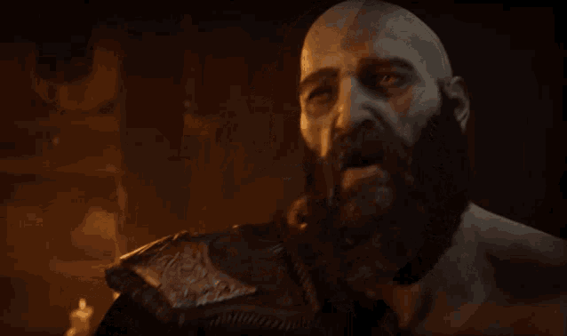 a bald man with a beard holds his hand to his face