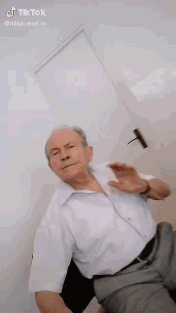 an elderly man in a white shirt and gray pants is dancing .