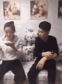a man and a woman are sitting on a couch . the woman is eating while the man is drinking .
