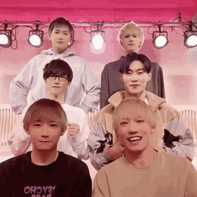 a group of young men are posing for a picture in front of a pink backdrop .