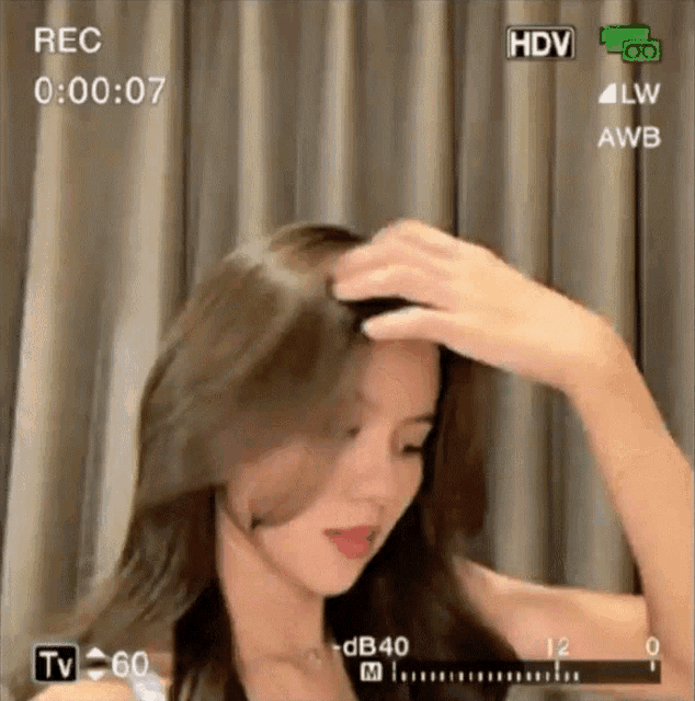 a woman adjusts her hair in front of a screen that says " rec "