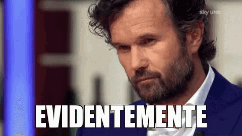 a man with a beard is wearing a blue suit and white shirt and has the word evidentemente written on his face .