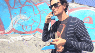 a man wearing sunglasses and a striped shirt talking on a phone