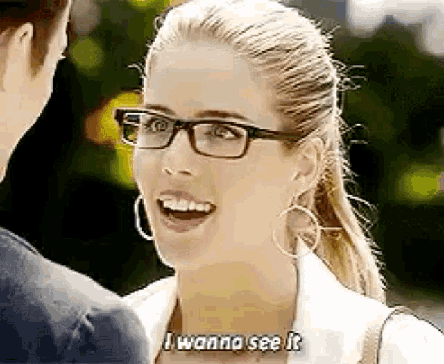 a woman wearing glasses is smiling while talking to a man .
