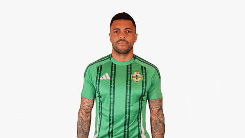 a man wearing a green adidas shirt holds up his arm