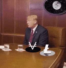 a man in a suit and tie sits at a table with a chinese symbol on the table