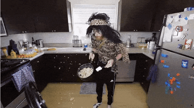 a man in a leopard print shirt is holding a pan in a kitchen