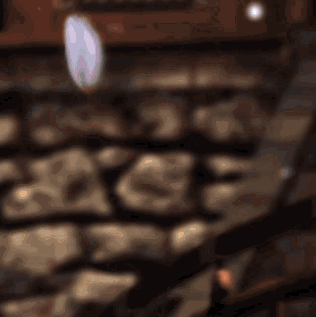 a blurry picture of a stone wall with a purple stone in the middle