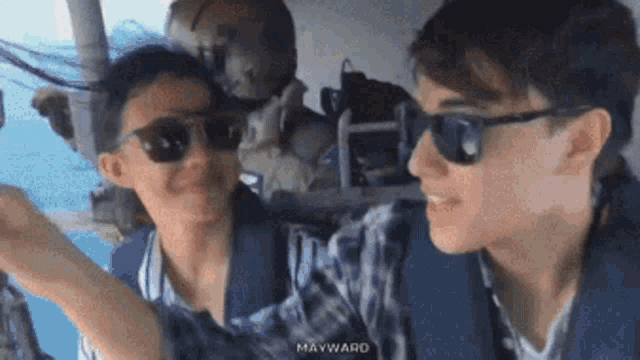 a man and a woman wearing sunglasses are sitting on a plane .