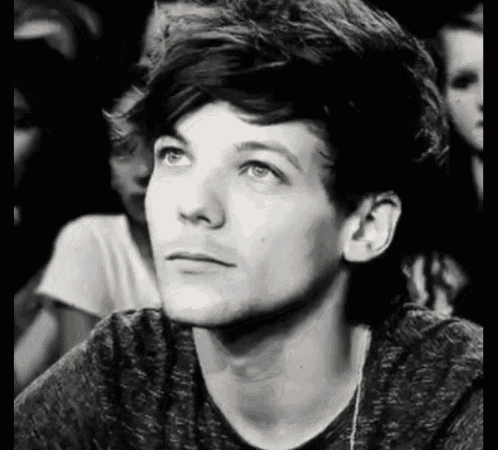 a black and white photo of a young man looking up at the sky