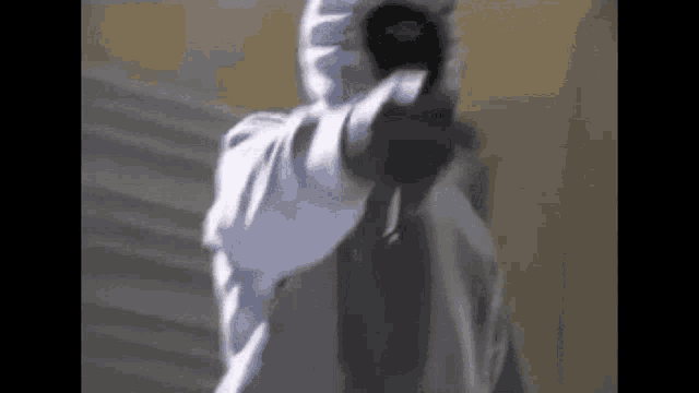 a man in a white hoodie is pointing a gun at someone .
