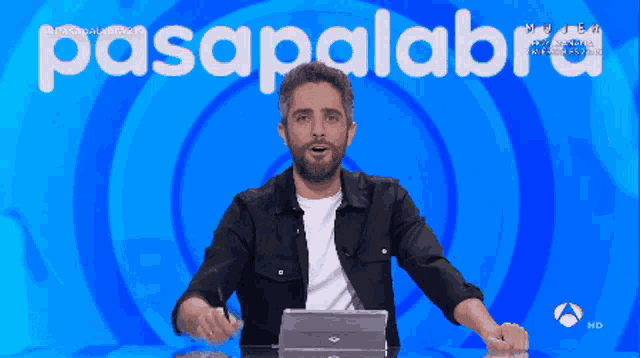 a man stands in front of a blue background with the word pasapalabra on it