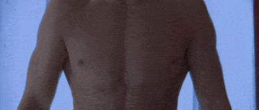 a shirtless man is standing in front of a window