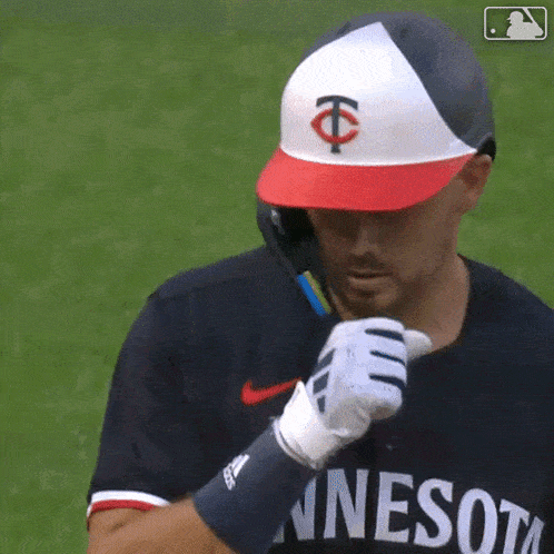 a baseball player wearing a minnesota jersey holds a bat
