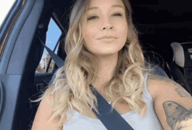 a woman with a tattoo on her arm is sitting in a car