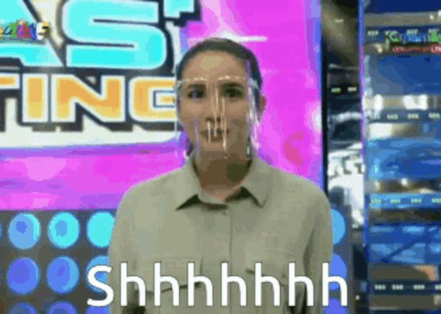 a woman wearing a face shield says shhhh on a screen