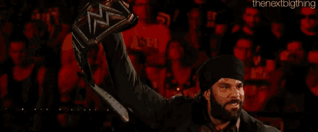 a man in a turban is holding up a wrestling championship belt ..