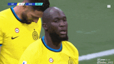 two soccer players in yellow jerseys are standing on a field