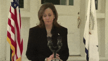 a woman stands in front of a podium that says the seal of the president