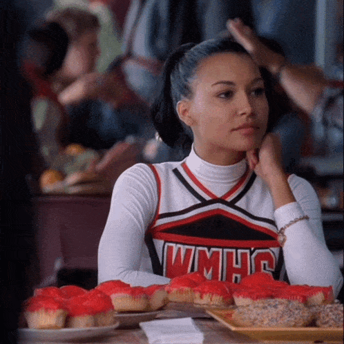 a cheerleader wearing a wmhs uniform sits at a table