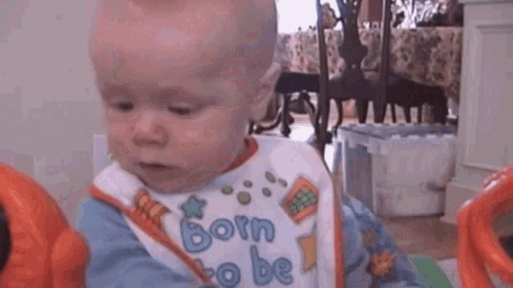 baby wearing a bib that says born to be