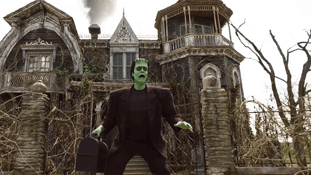 a man dressed as frankenstein is standing in front of an old house